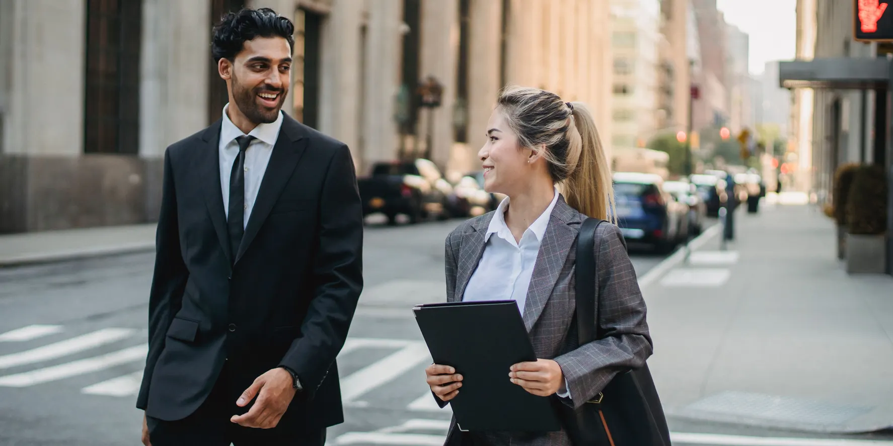 Two business executives with briefcases walking to a client meeting in a downtown financial district